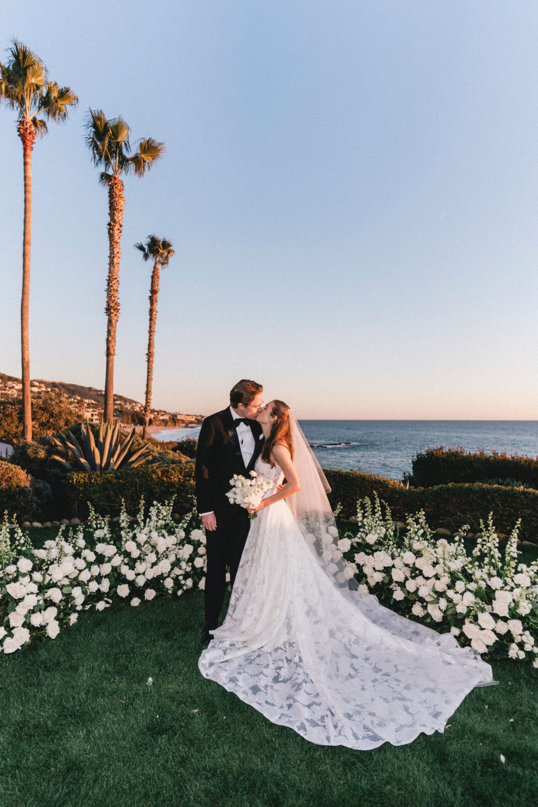 The bride and groom are kissing under a sunset.