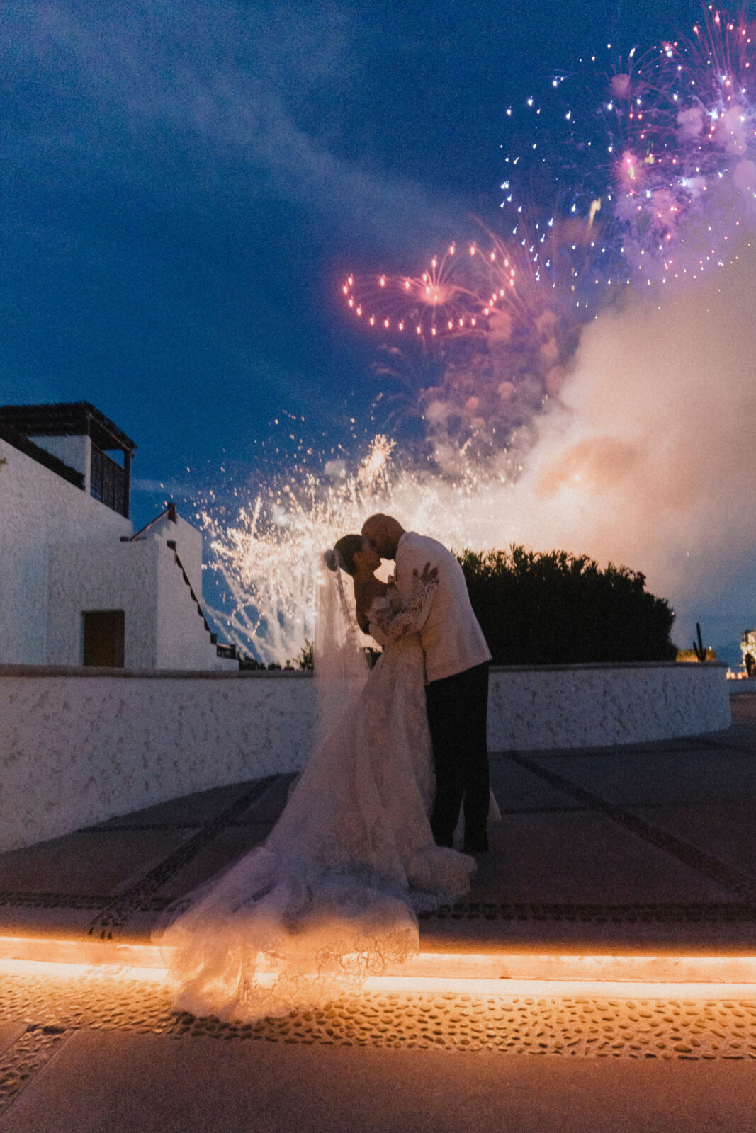 bride and groom kissing under the fireworks