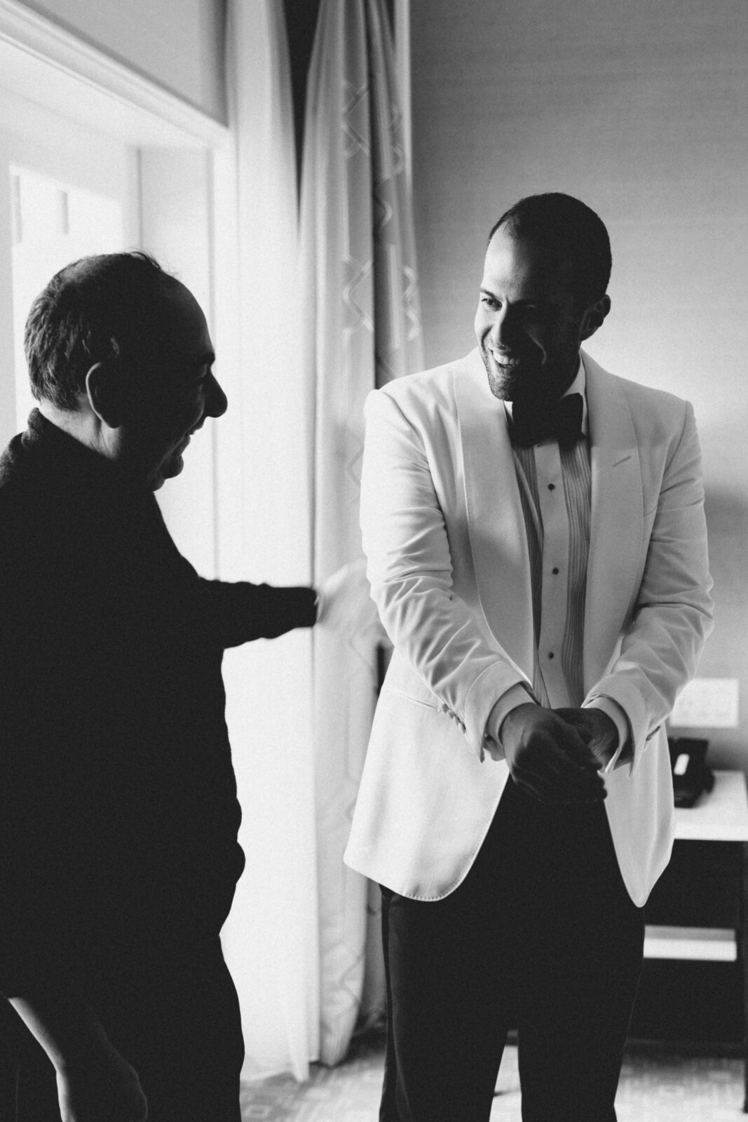 groom and father smiling at each other 