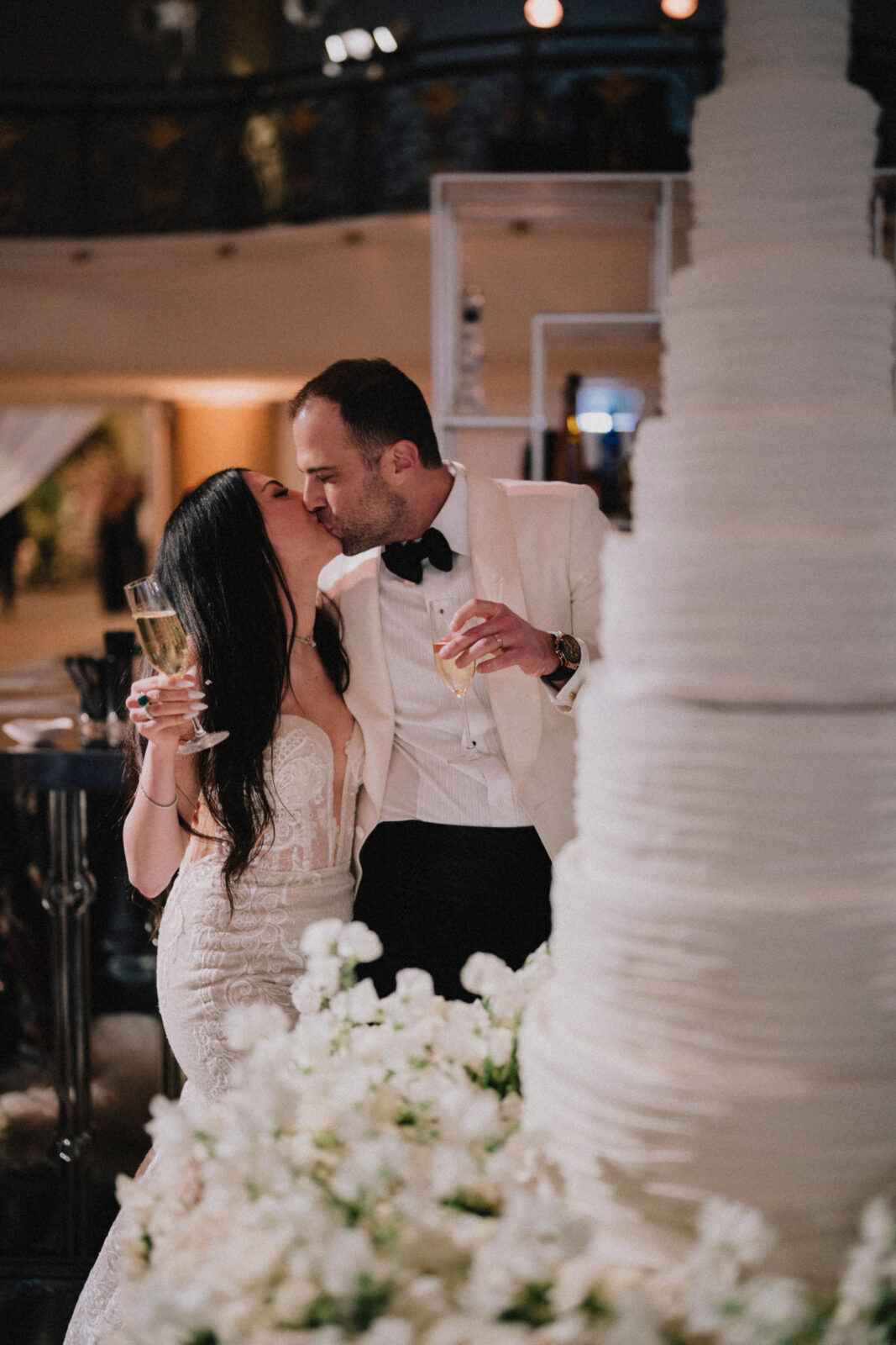 bride and groom kissing behind the wedding cake