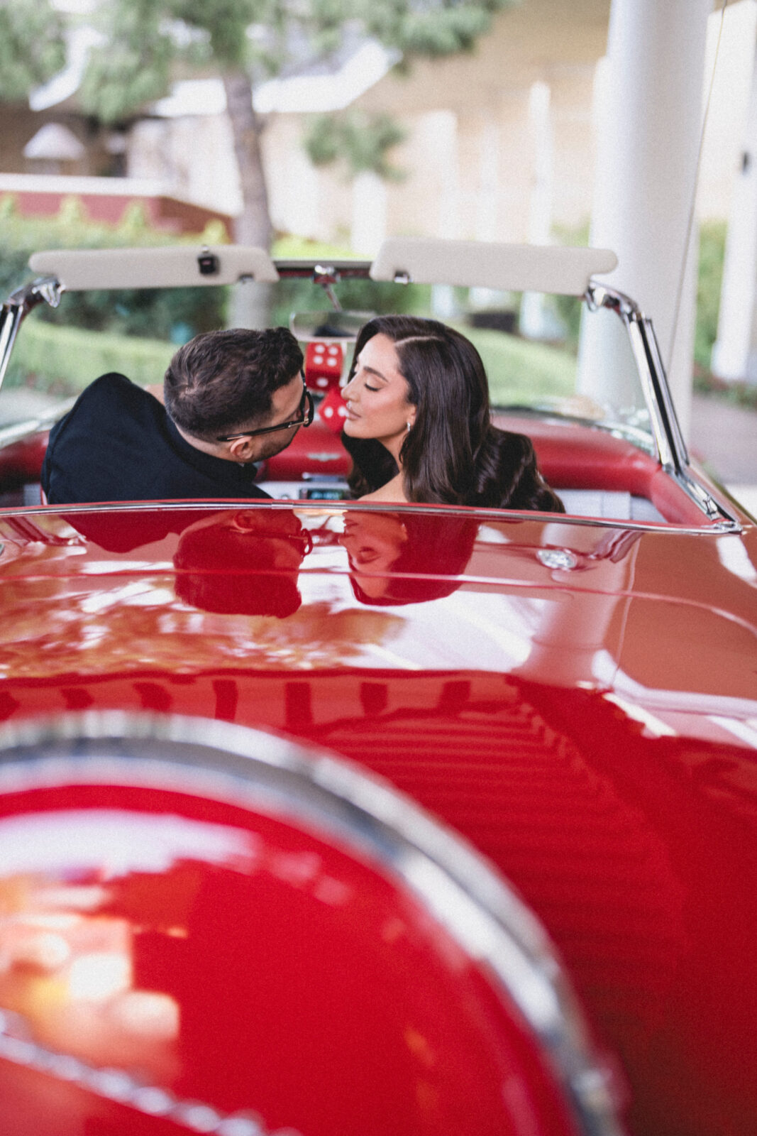 bride and groom riding a red sportscar